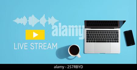 Live-Stream-Konzept mit einem Laptop, einem Smartphone und einer Tasse Kaffee auf blauem Hintergrund, mit Wiedergabetaste und Tonwellen Stockfoto