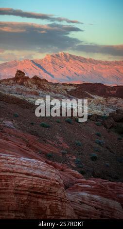 Bei Sonnenuntergang leuchtet Nevadas Valley of Fire, während das karmesinrote Licht seine zerklüfteten Berge und feurigen Sandsteinformationen erleuchtet Stockfoto