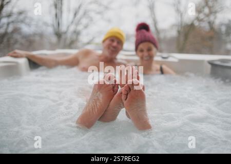 Schließen Sie sich den Füßen eines Seniorenpaares an, das an kalten Wintertagen im Wannen-Whirlpool badete. Stockfoto