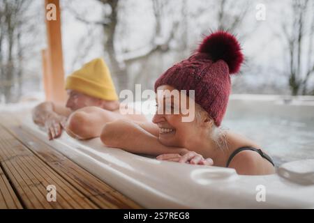Seniorenpaar baden im Wannen-Whirlpool an kalten Wintertagen. Romantischer Wellness-Kurzurlaub mit Spa am Valentinstag-Wochenende. Stockfoto