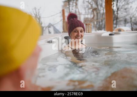 Seniorenpaar baden im Wannen-Whirlpool an kalten Wintertagen. Romantischer Wellness-Kurzurlaub mit Spa am Valentinstag-Wochenende. Stockfoto