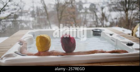 Rückansicht eines Seniorenpaares, das an kalten Wintertagen im Whirlpool badete. Banner mit Kopierbereich Stockfoto
