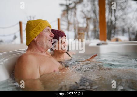 Seniorenpaar baden im Wannen-Whirlpool an kalten Wintertagen. Romantischer Wellness-Kurzurlaub mit Spa am Valentinstag-Wochenende. Stockfoto