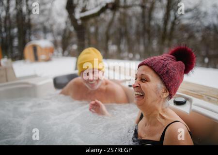 Seniorenpaar baden im Wannen-Whirlpool an kalten Wintertagen. Romantischer Wellness-Kurzurlaub mit Spa am Valentinstag-Wochenende. Stockfoto