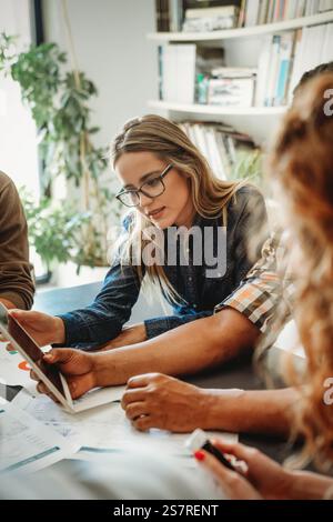Lächelnd treffen sich verschiedene Kollegen in einem Brainstorming in der Vorstandsetage, um gemeinsam Finanzstatistiken zu diskutieren Stockfoto