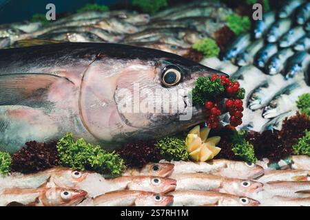 Ein großer Fisch mit roten Beeren und Blattgemüse auf einem Fischmarkt Stockfoto