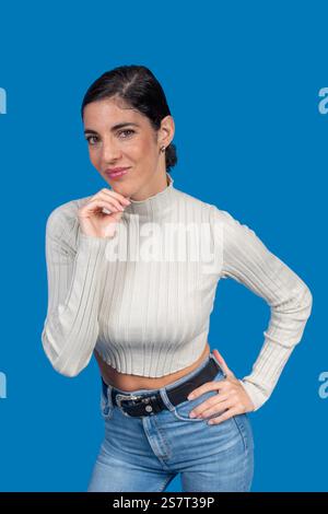 Studio-Porträt einer stilvollen jungen Frau, die selbstbewusst vor einem leuchtend blauen Hintergrund posiert Stockfoto