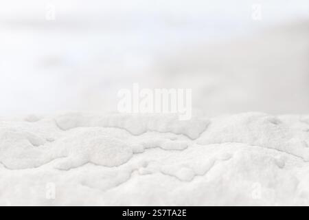 Weiche weiße Schneestruktur mit verschwommenem Hintergrund für eine minimalistische Winteratmosphäre. Perfekt für saisonale Projekte und Urlaubsthemen Stockfoto
