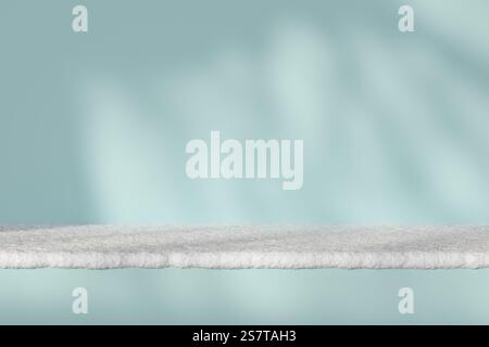 Minimalistisch verschneite Oberfläche vor weichem blauem Hintergrund mit sanften Schatten für eine ruhige Winteratmosphäre. Perfekt für saisonale Designs Stockfoto