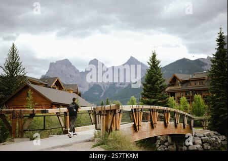 Mann, der auf einer Holzbrücke mit Bergen in Canmore, Kanada, läuft Stockfoto