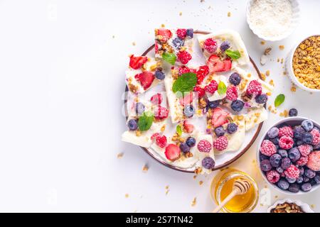 Hausgemachte gefrorene Joghurtrinde, Alternative gesunde Keto Diät Eis aus griechischem Joghurt, frische Beeren, Nüsse, Müsli, Honig, auf Backblech Deko. Stockfoto