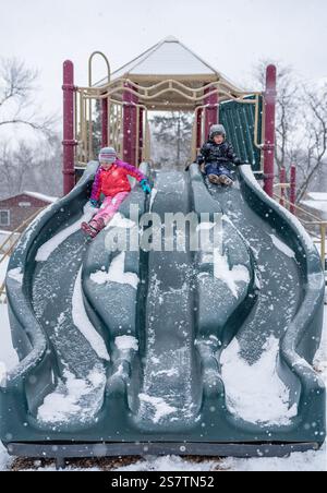 Kinder rutschen auf einer schneebedeckten Rutsche herunter Stockfoto