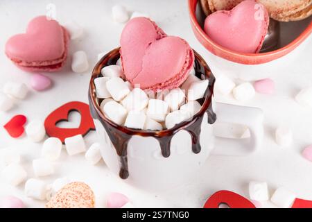 Valentinstag heiße Schokolade oder Kaffee Latte Becher mit Schokoladennebel, herzförmigem Marshmallow und Macaron Keks. Süße Leckereien, Rezeptidee, Stockfoto