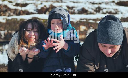 Glückliche Familie, die verspielte Momente im Schnee genießt und sich in der Wärme eines sonnigen Wintertages voller Lachen und Freude erfreut Stockfoto