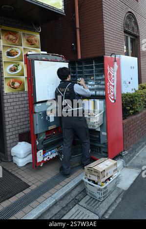 Ein Mann, der einen Coca-Cola-Automaten in Omiya, Saitama, Japan lädt. Stockfoto