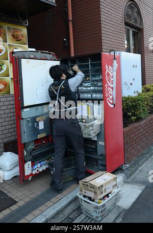 Ein Mann, der einen Coca-Cola-Automaten in Omiya, Saitama, Japan lädt. Stockfoto