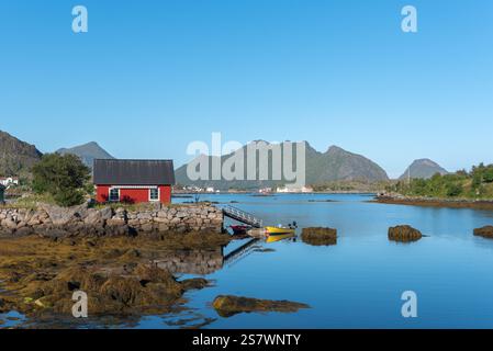 Blick auf die Landschaft der Skotnesosen Bucht mit traditionellem rotem Fischerhaus, genannt rorbu, Ballstad, Lofoten, Norwegen, Europa Stockfoto