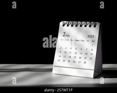 Ein Tischkalender für die Planung und Erinnerung im Februar 2025, der auf einem weißen Tisch steht, dunkler Hintergrund mit Kopierraum. Kleiner Kalender mit der Seite des Stockfoto