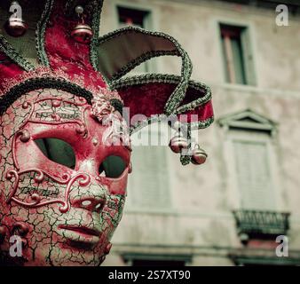 Musikalische Maske. Wehmut des venezianischen Karnevals. Venezianische Musik Karnevalsmaske und alter palazzo im Hintergrund. Venedig, Italien. Retro-Foto. Stockfoto