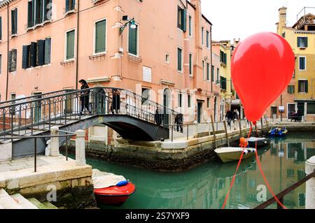 VENEDIG, ITALIEN - 14. FEBRUAR 2015: Roter Ballon verloren bei der Karnevalsparty am Kanalgeländer. Stockfoto
