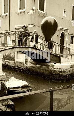 VENEDIG, ITALIEN - 14. FEBRUAR 2015: Ballon bei der Karnevalsparty am Kanalgeländer verloren. Historisches Foto von Sepia Stockfoto