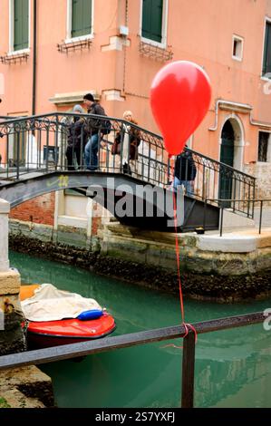 VENEDIG, ITALIEN - 14. FEBRUAR 2015: Roter Ballon verloren bei der Karnevalsparty am Kanalgeländer. Stockfoto
