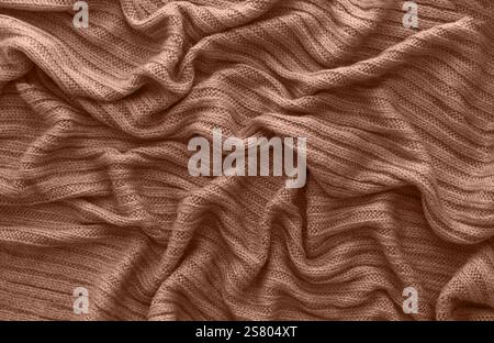 Brauner, zerknitterter Strickschal oder Pullover, Draufsicht. Texturhintergrund von warmgehäkeltem Bekleidungstextil. Strickware. Mokka Mousse Color Stockfoto