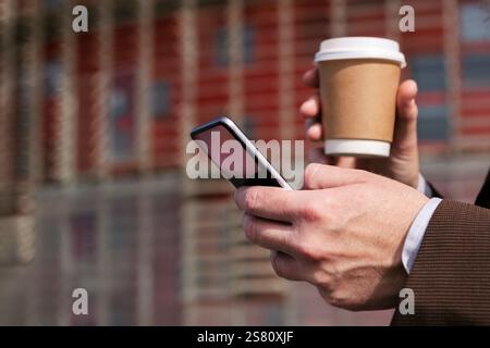Hände eines Mannes mit Kaffee und Handy-Browsing Stockfoto