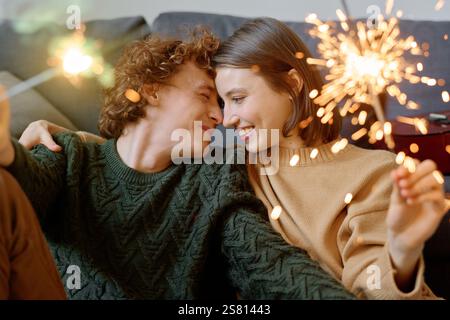 Mittlere Nahaufnahme eines schönen Kuschelpaares mit beleuchteten bengalischen Lichtern in den Händen Stockfoto
