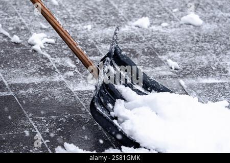 Ein Schneepflug liegt auf dem Boden mit Schnee. Der Schnee stapelt sich in einem Haufen Stockfoto