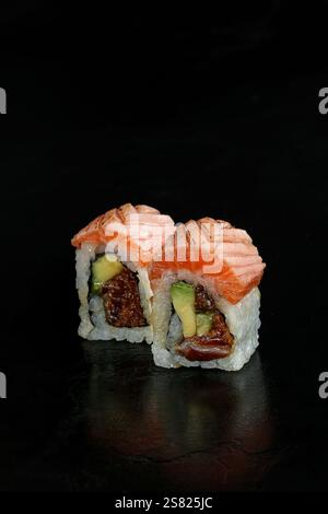 Nahaufnahme von zwei Sushi-Brötchen gefüllt mit Avocado, Lachs und anderen frischen Zutaten, garniert mit Mikrogrün, präsentiert auf schwarzem Hintergrund. Stockfoto