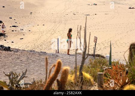 Junge Frau in einem kleinen grünen Bikini am Strand von El Cotillo, Fuerteventura. Vom Dezember 2024. Stockfoto