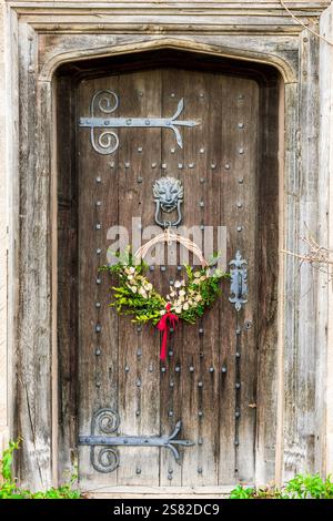 Alte rustikale Tür mit schmiedeeisernen Elementen und hängenden Blumen Stockfoto