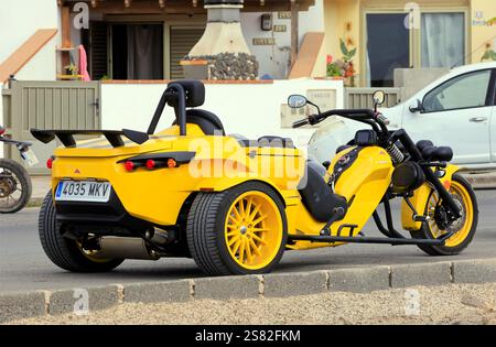Gelbes dreirädriges Rewaco-Motorrad parkt am Straßenrand, El Cotillo, Fuerteventura. Vom Dezember 2024. Stockfoto
