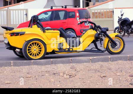 Gelbes dreirädriges Rewaco-Motorrad parkt am Straßenrand, El Cotillo, Fuerteventura. Vom Dezember 2024. Stockfoto