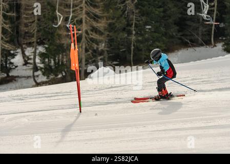 Gruppe von Menschen, die an einem sonnigen Wintertag in den Bergen Ski fahren. Skiunterricht mit ortskundigen Lehrern. Kinder lernen Skifahren mit einem Lehrer. Kinder Stockfoto