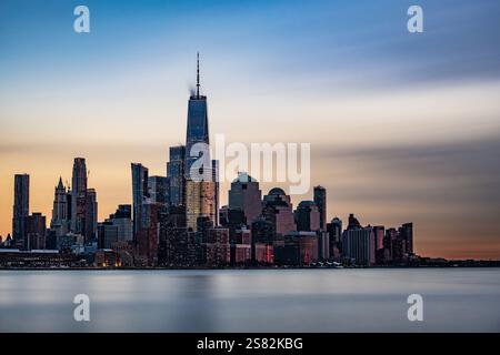 Lange Sicht der Skyline von Manhattan aus Hoboken, New Jersey, in der Abenddämmerung. Das ruhige Abendlicht unterstreicht die berühmten Wolkenkratzer der Stadt Stockfoto