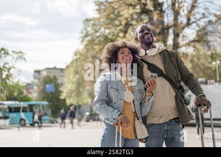 Afroamerikanisches Paar überprüft den Fahrplan Ankunft Abfahrtskarte an einem Bahnhof. Informations-, Transport- und Tourismuskonzepte. Stockfoto