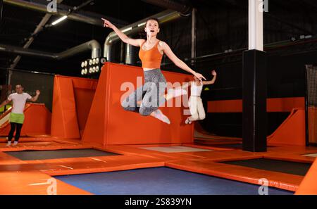 Glückliche Frau mittleren Alters, die auf Trampolinen in einem Sporthalle trampoliniert und springt, Workout und modernes Unterhaltungskonzept Stockfoto