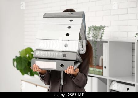 Eine junge Frau mit einem Stapel Akten im Büro. Nahaufnahme Stockfoto
