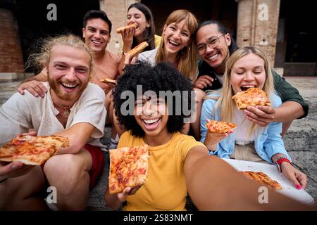 Lustige Gruppe junger Leute und sie haben Spaß beim Pizza essen in der touristischen Stadt Stockfoto