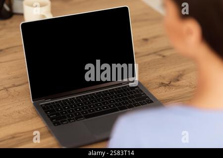 Frau arbeitet auf Laptop mit leeren schwarzen Bildschirm für mockup Stockfoto