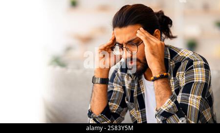 Nahaufnahme eines traurigen arabischen Mannes, der seinen Kopf berührt Stockfoto
