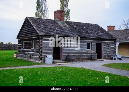 Eine kleine Blockhütte mit einem Kamin und einer Veranda. Das Gebäude ist von einer Grasfläche umgeben Stockfoto
