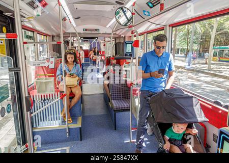 Barcelona Spanien Poblenou, Avinguda Diagonal, an Bord im Innenraum, Fahrgäste, Vater Sohn Kinderwagen Frau, Lesen Handy überprüfen, Sitzen Stockfoto