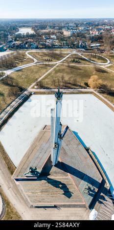 Aus der Vogelperspektive des Siegesdenkmals in Riga, Lettland, mit Sternenobelisken, gefrorenem Wasser, geometrischen Parkwegen und Wohngebäuden Stockfoto