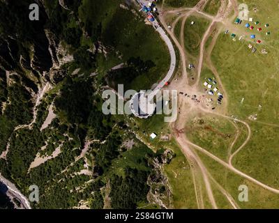 Aus der Vogelperspektive das Friendship Monument auf einer Klippe in der Nähe des Georgian Military Highway mit Wegen, Fahrzeugen und vielseitigem Land in der Umgebung Stockfoto