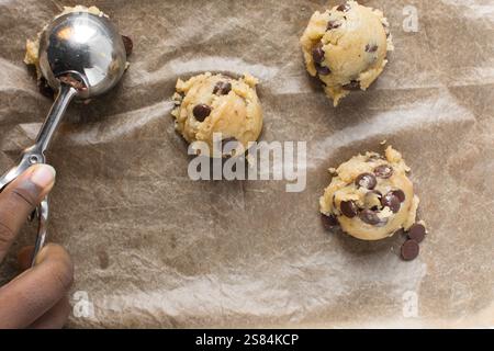 Blick von oben auf den Schokoladen-Chip-Cookie-Teig, der auf ein Backblech geschaufelt wird, Blick von oben auf den hausgemachten Schokoladen-Chip-Cookie-Teig, Prozess der Herstellung von ch Stockfoto