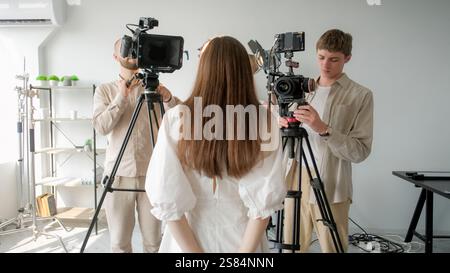 Aufnahmemodell. Backstage Studio. Mädchen mit lockeren Haaren steht vor Kameras. Frau posiert Foto-Video-Film-Interview-Produktion. Stockfoto