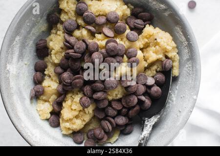 Blick von oben auf Chocolate Chip Cookie Teig, Draufsicht auf hausgemachten Chocolate Chip Cookie Teig in einer Schüssel auf weißem Hintergrund, Prozess der Schokoladenherstellung Stockfoto